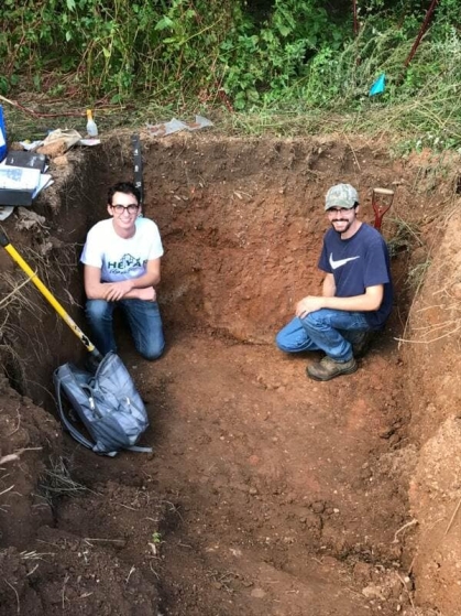 Two students in a hole sampling soil.